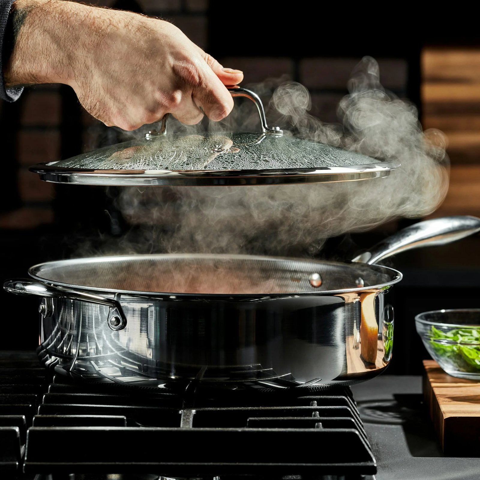 Lifting a glass lid off a steaming HexClad deep sauté pan